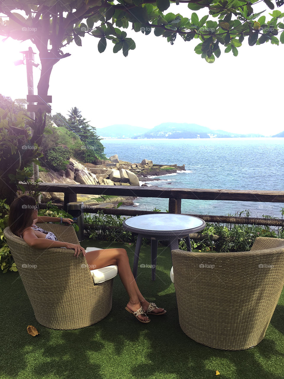 Young woman enjoying the beautiful seascape at the shadow of the tropical trees 