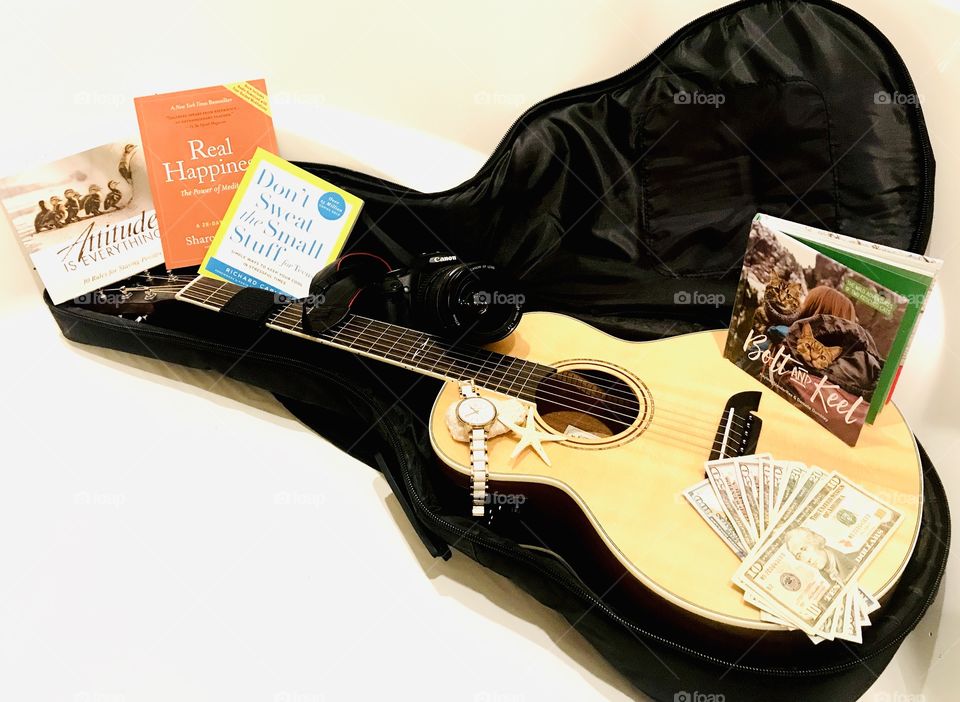 Fun photo of guitar with guitar case filled with books, money, and camera for trip! 