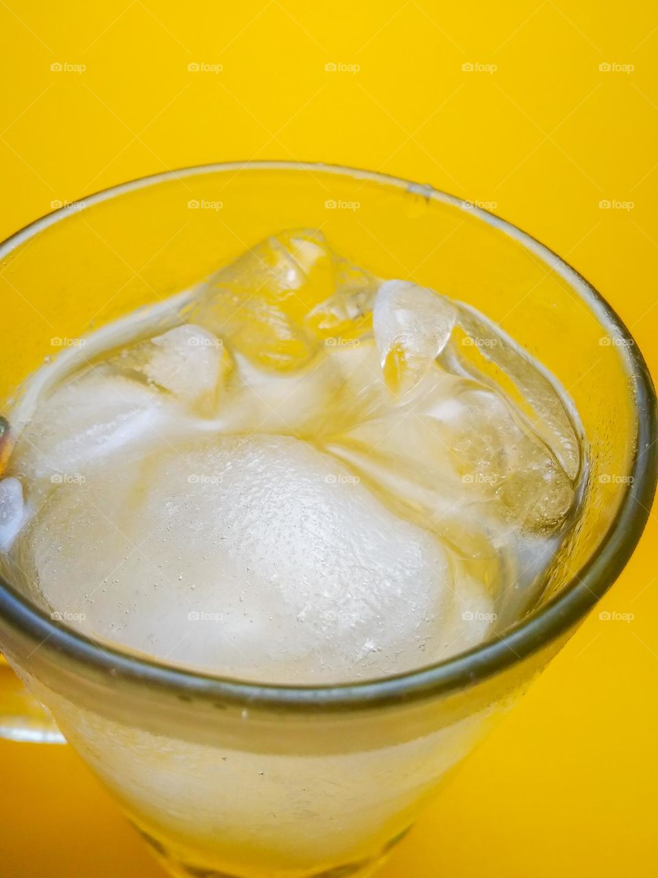 A glass of water and a few ice cubes are cold and refreshing to quench thirst in hot weather.