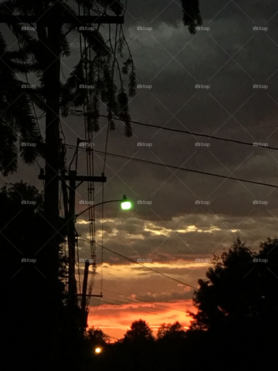Sunrises and Sunsets of the USA! View on roadway looking at sunset clouds. These are in orange and highlighted by white edged clouds. Darkness is coming!