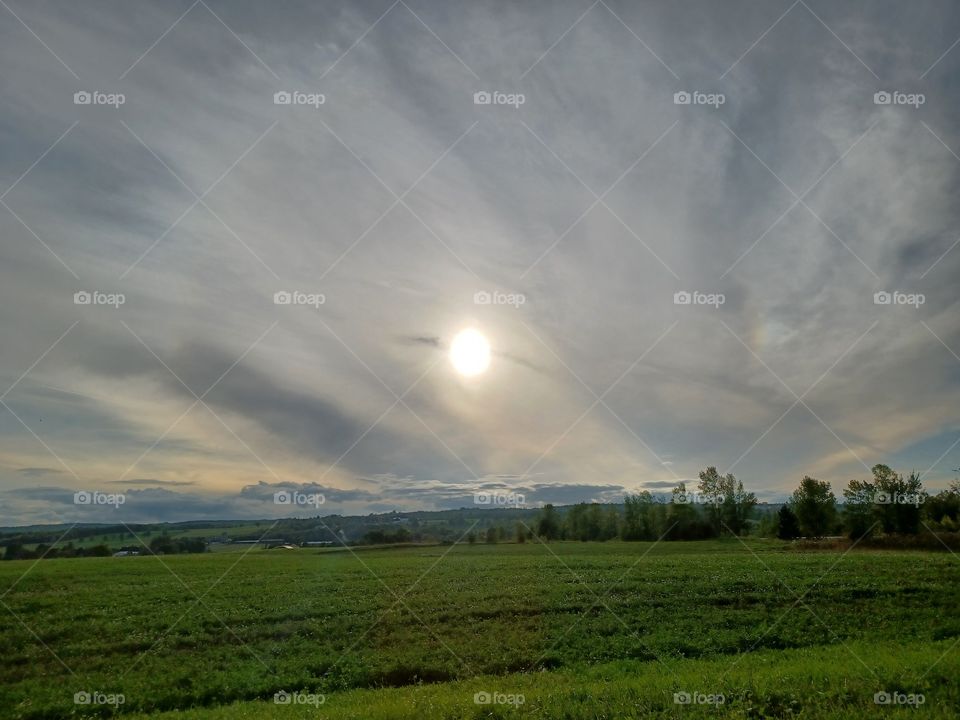 The Sun behind thin grey clouds.