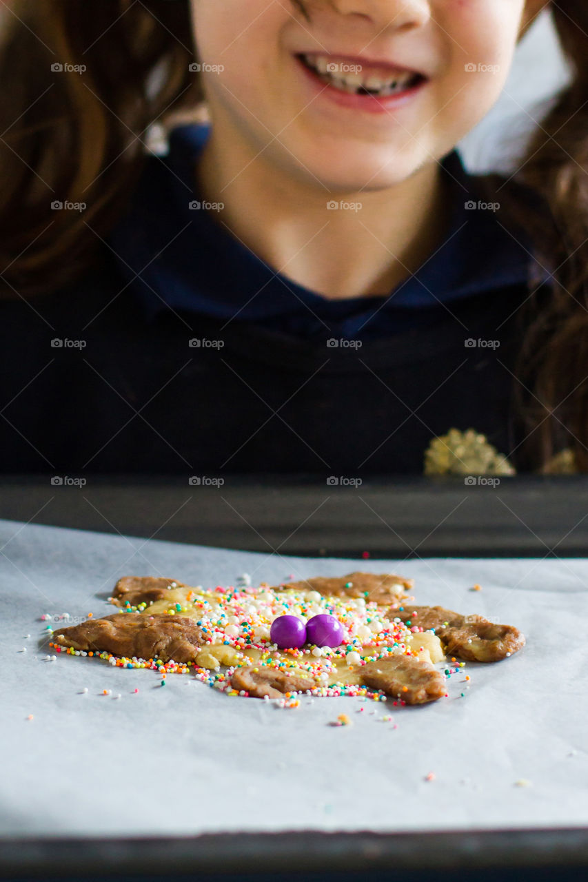 Fun and education at home - we made cookies to explain the corona virus to the kids. Image of girl holding a tray ready to bake her germ like cookie