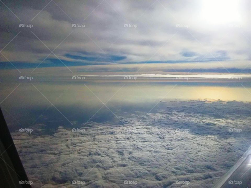looking out the window of a plane at  clouds above and below
