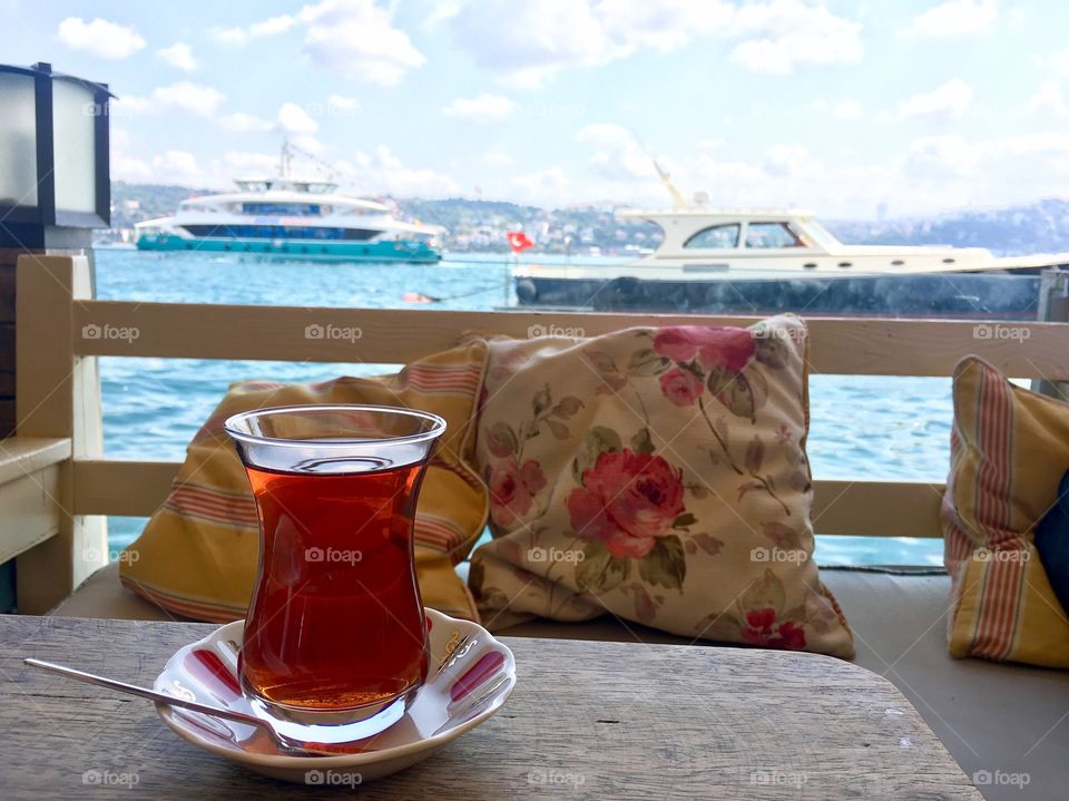 Cup of turkish tea on a wooden table and with nice cruises view