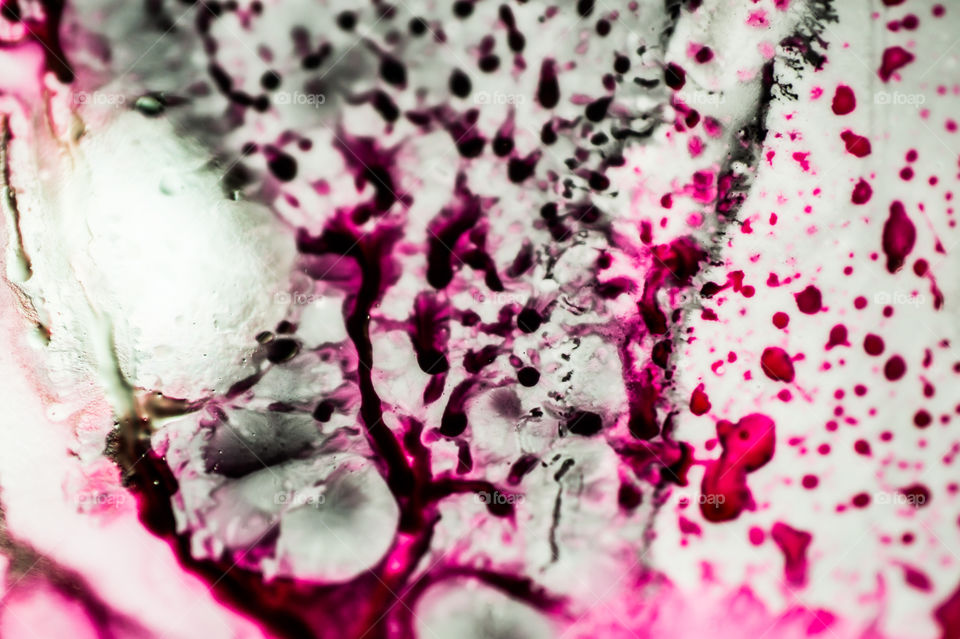 Black and pink refill ink spilled onto the white sink and the ink mixed into abstract blobs and patterns.