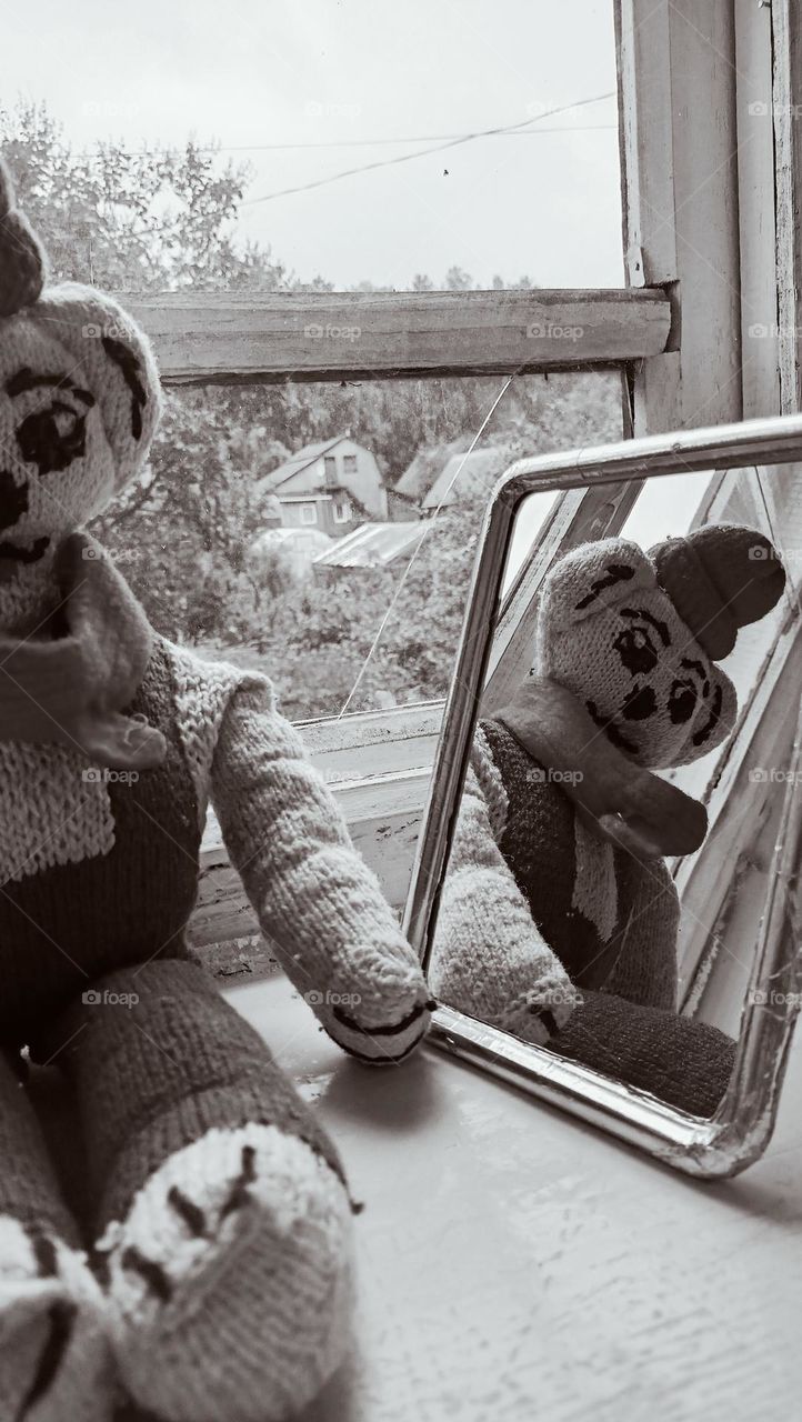 window to the past, wooden frame, glass, old knitted toy, toy on the windowsill, joy in the mirror, black and white photo, village