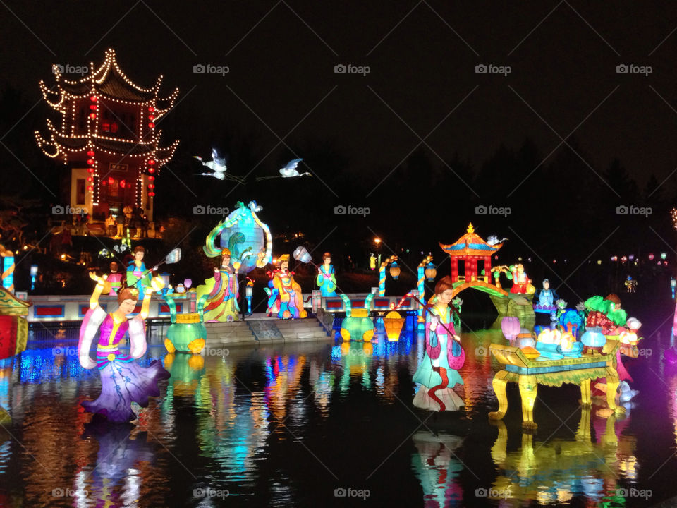 Chinese figurines reflect in water at night