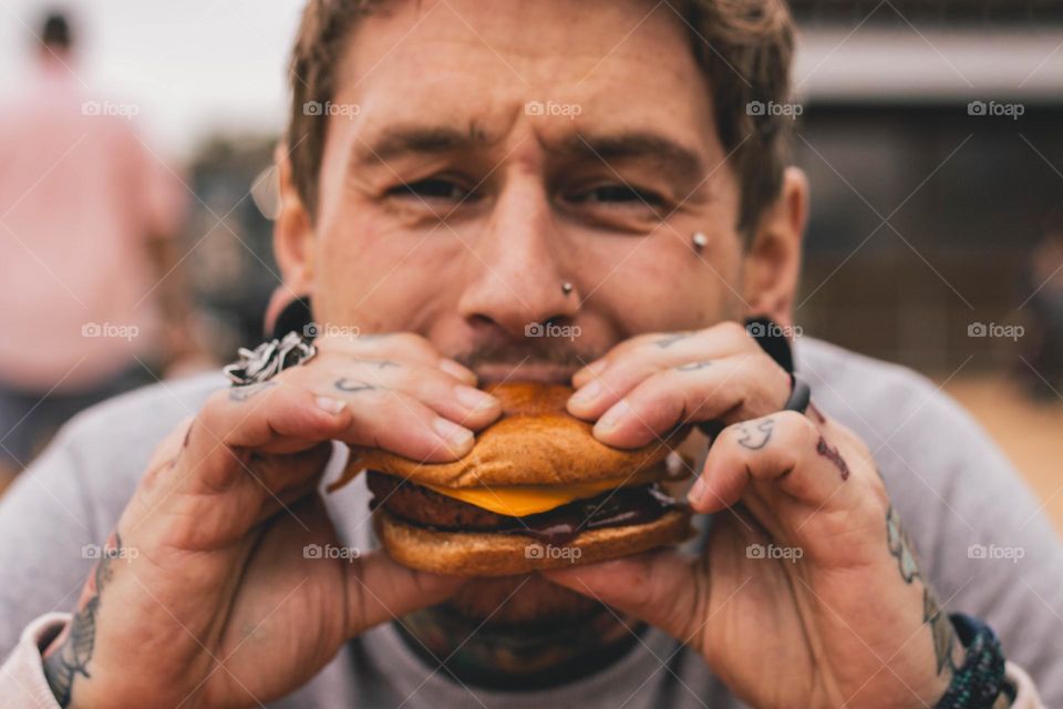 Tattooed man taking a bite of a burger