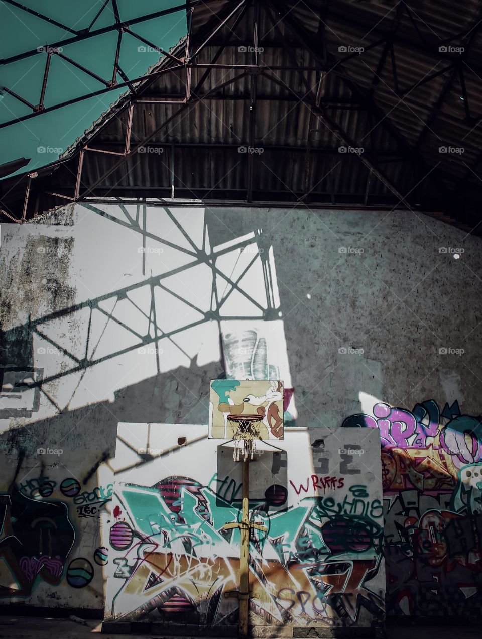 basketball room decorated with murals and graffiti with sun shadows from the tiled roof