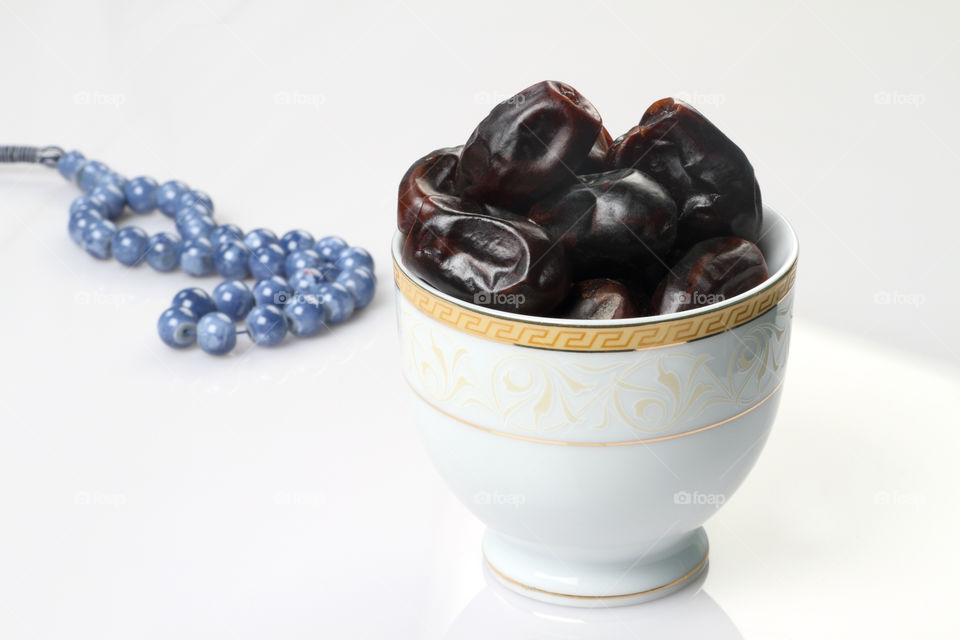 Arabian date fruit in a white bowl with rosary