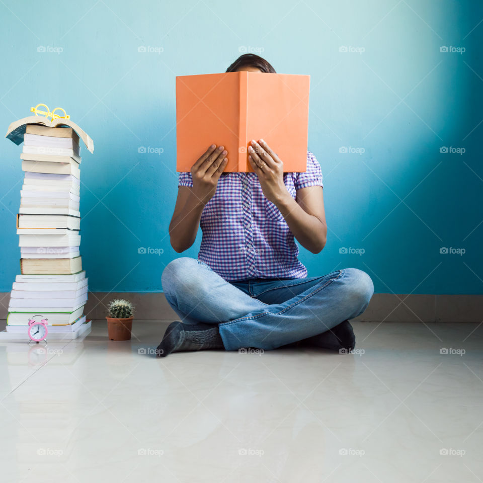 Teenager reading orange colored book with blue color background isolated.Orange x blue.