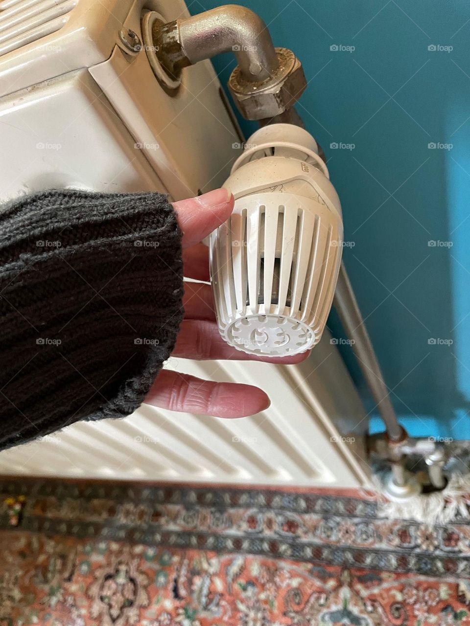 Close-up of a hand turning a heating thermostat