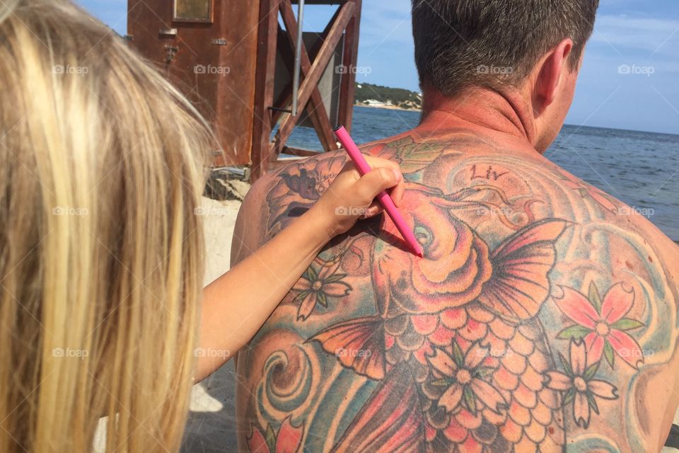Girl colouring in a back tattoo