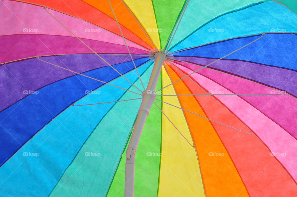 Under a colorful beach umbrella.