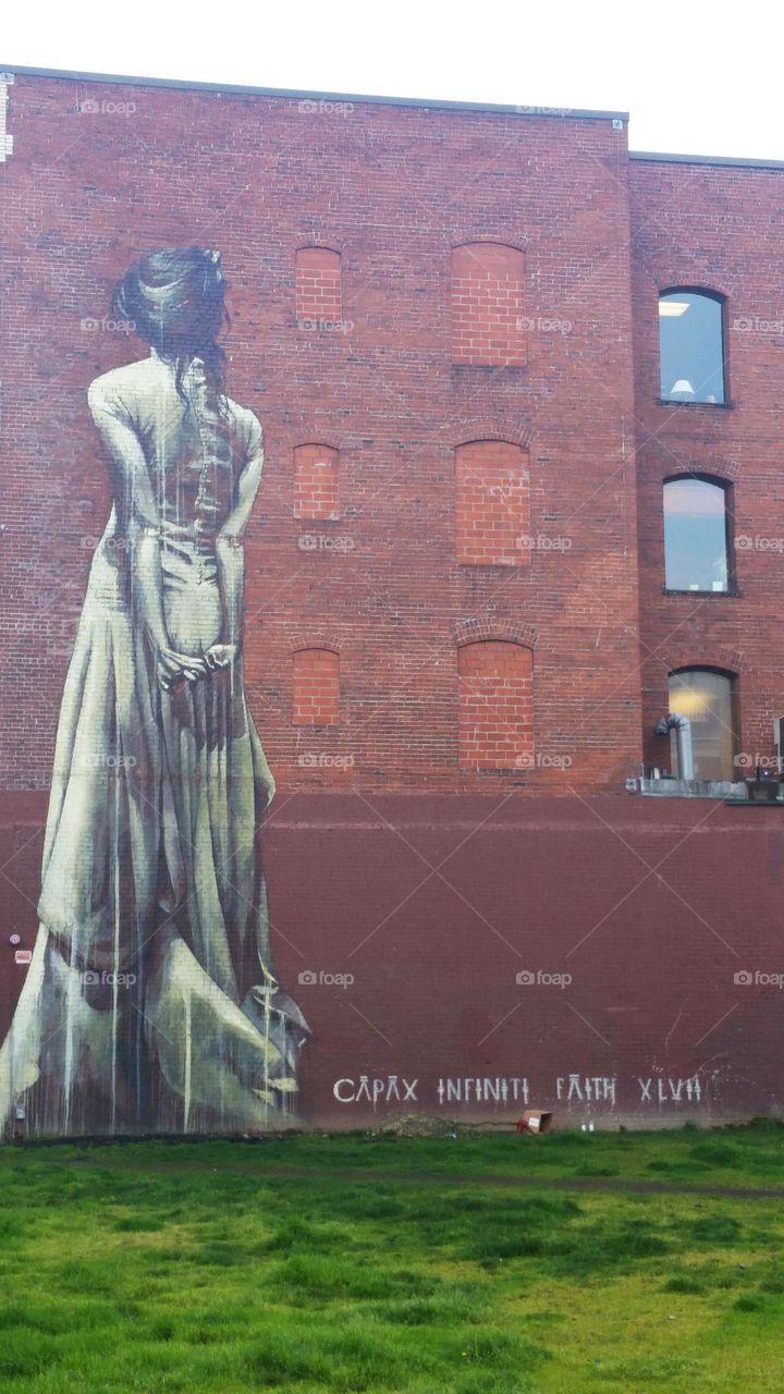 captivating brick wall art mural of gray woman seen from behind in Portland Oregon