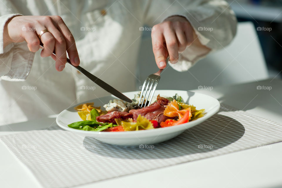 close-up of a young man eating a salad in a light kitchen