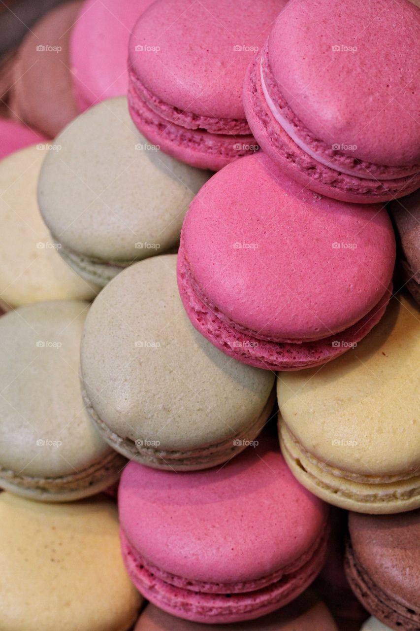 A plate full of colourful macaroons that are piled up and filling the frame.