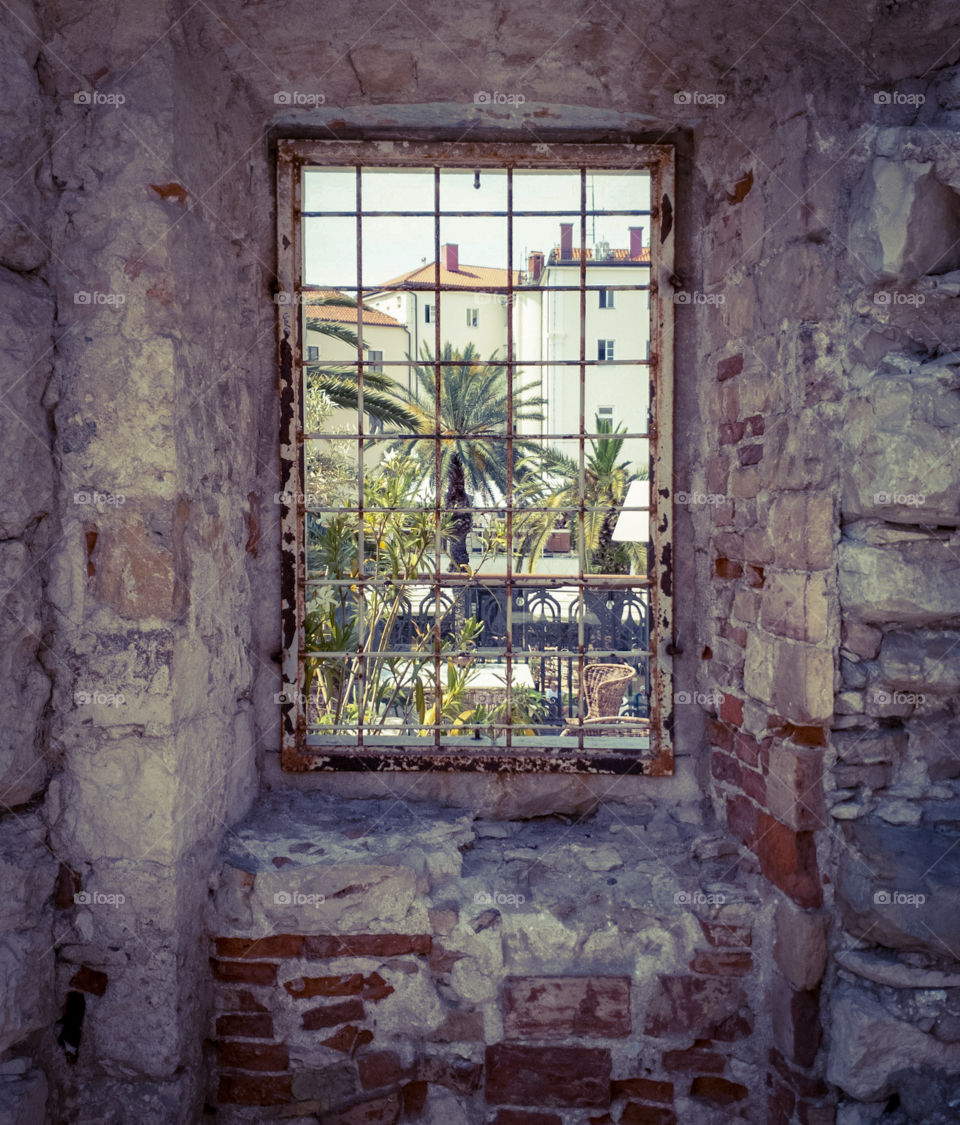 Split  Croatia.  Summer landscape of a southern European resort town through a barred window of an old ruined building