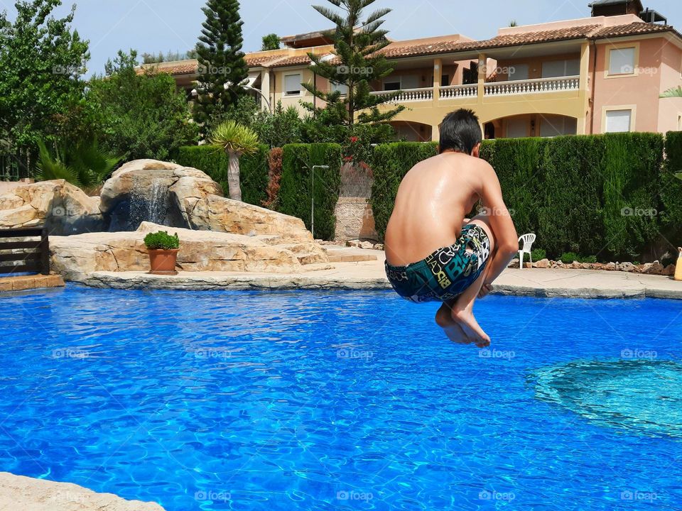 Boy jumping into a swimming pool