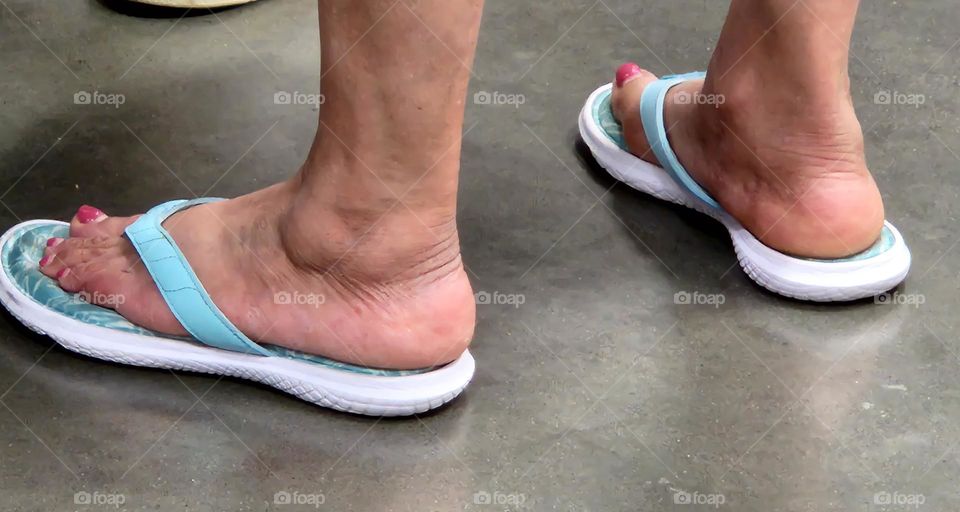 woman's feet wearing flip flop sandals on concrete floor in Summer