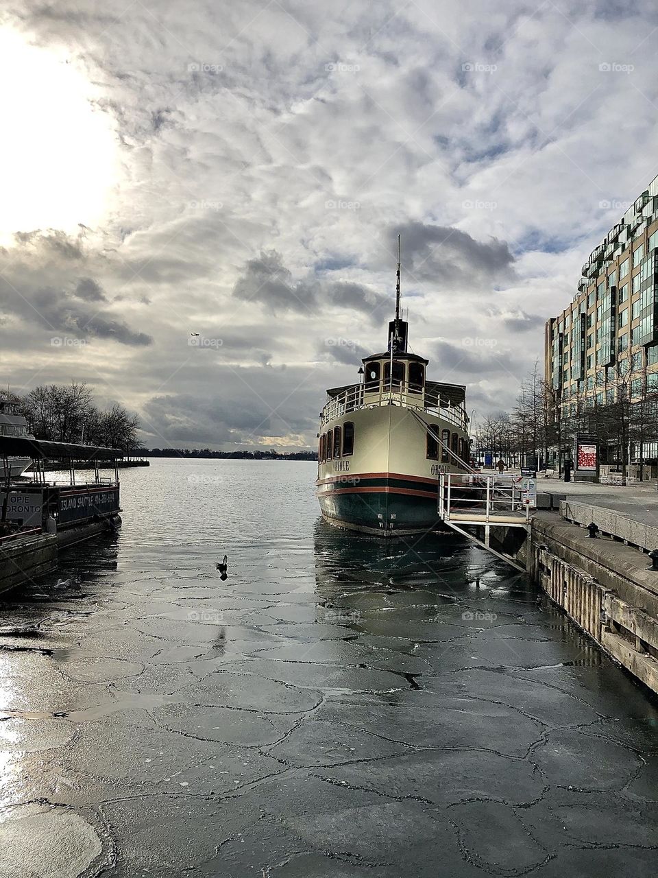 Toronto harbourfront , boat and pier in the morning sun peaking through the clouds 