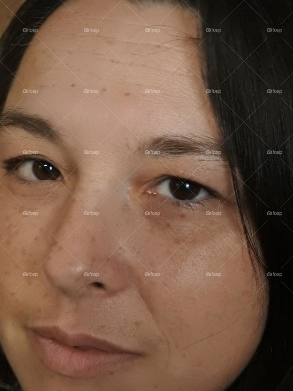 Face skin in the forties of a woman with freckles and brown hair closeup.