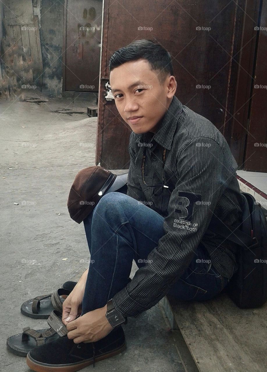 A man is sitting wearing shoes, about to go to work.