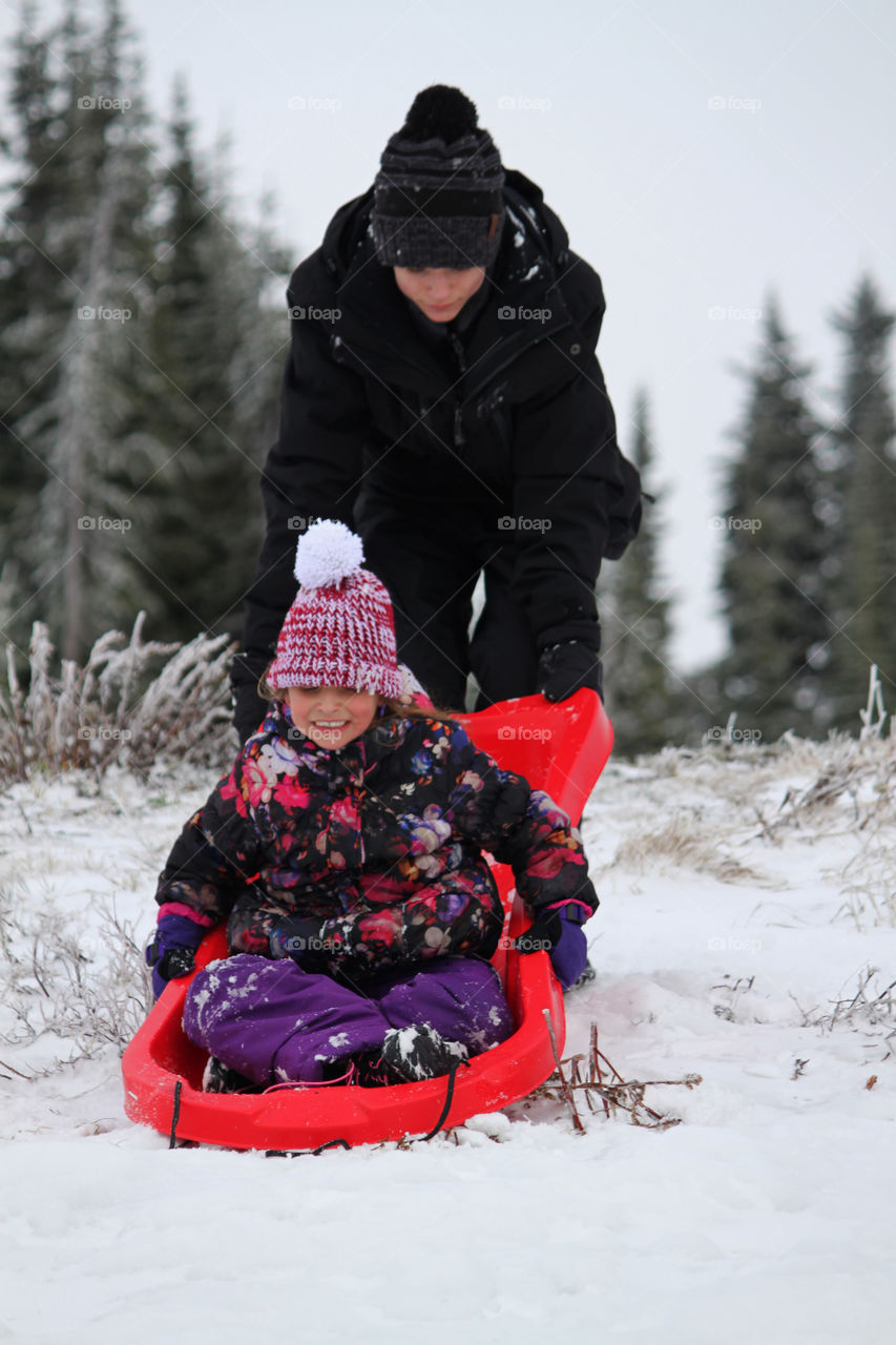 Big brother having fun sledding with little sister