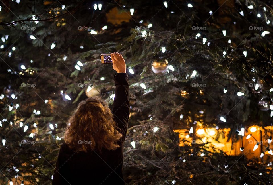 Rear view of a woman taking selfie in mobile phone