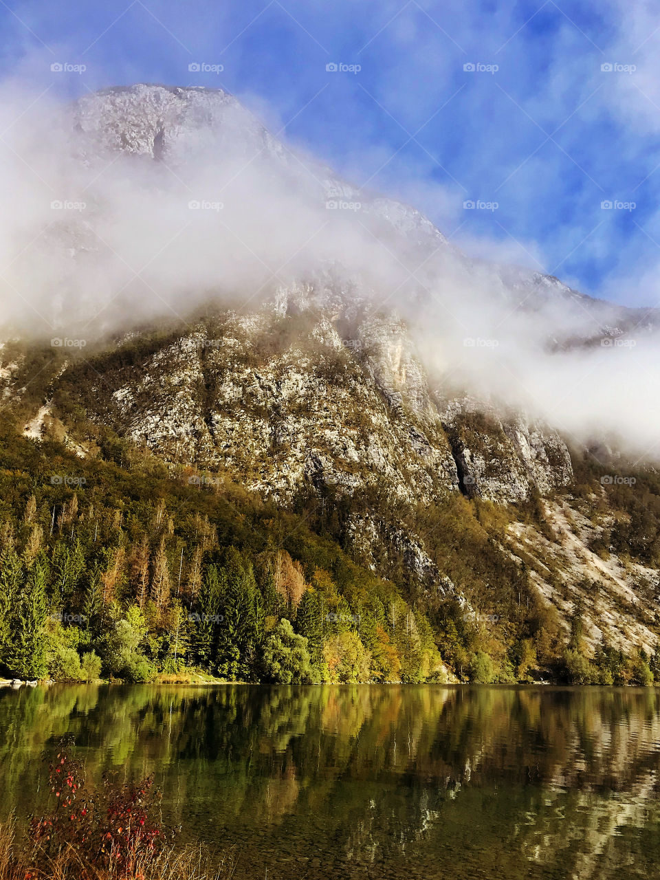 Scenic view of autumn Alps landscape with lake Bohinj in Slovenia and foggy mountains in early morning in fall season. Slovenia travel.