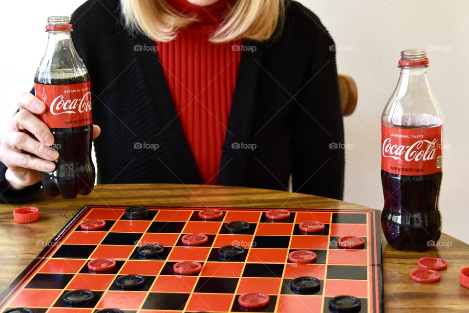 Woman hold Coca-Cola and playing checkers 