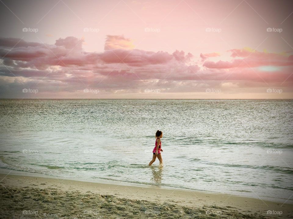 Little girl in the blue ocean water,  As the sunsets 🌆