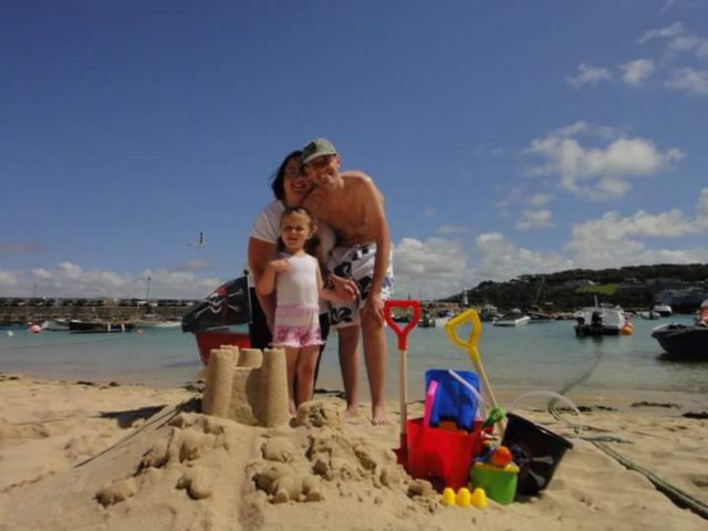 family photo on st ives beach,
with sandcastle ,
blonde, Caucasian little girl , man, woman , parents and daughter . looking forwards , St. Ives , cornwall, South,  West,  of, England,  United Kingdom,  of, great Britain,  
summer time, sunshine