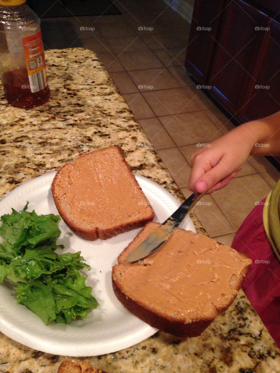 Make me a sandwich. Person making a peanut butter and honey sandwich