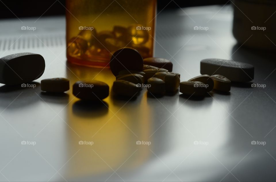 Prescription pills and pain medication sitting on a closed laptop computer highlight the growing opioid crisis in America.