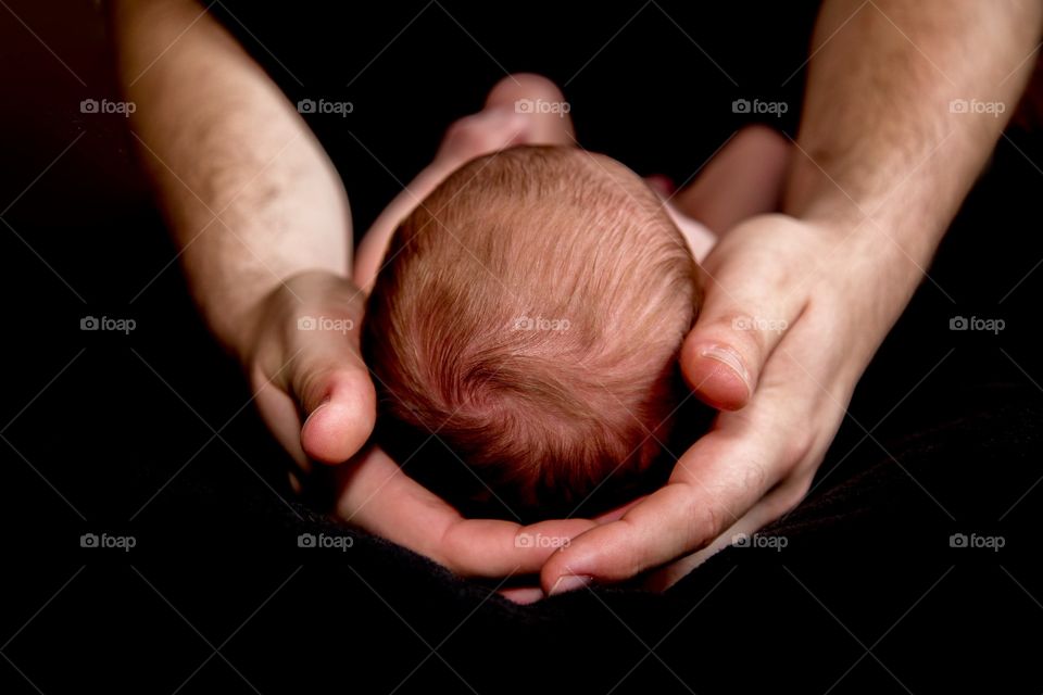 Father holding the head of baby laving caring