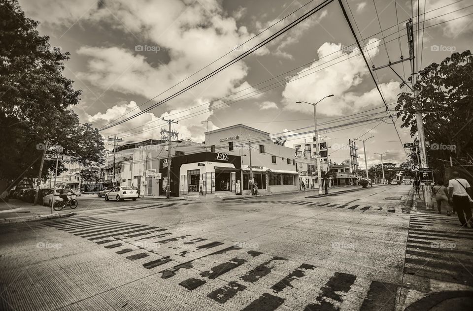 Black and white photo of a cross between streets of playa del Carmen in Mexico completely empty in wide angle shot.
