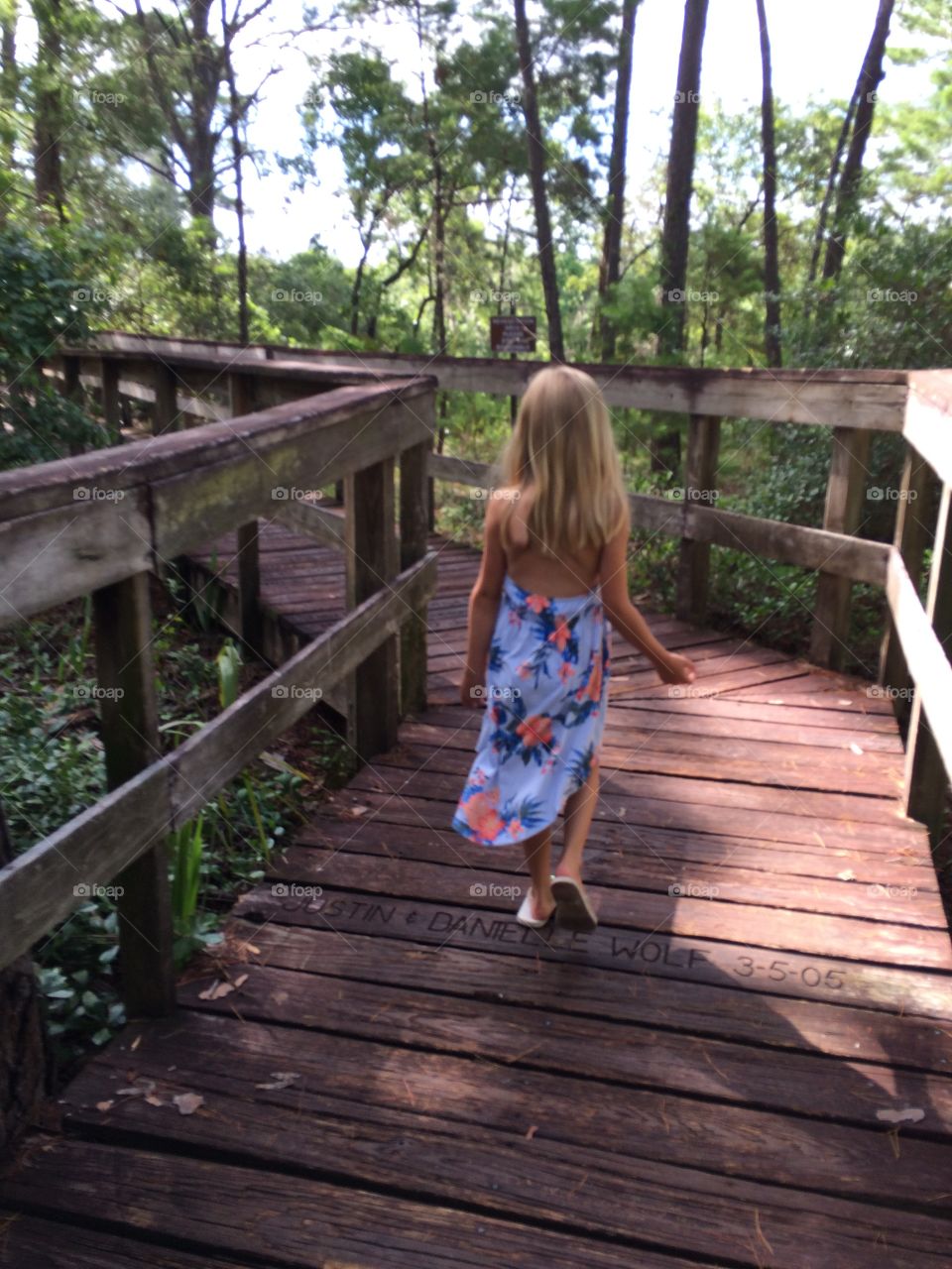little girl walking in a wooden pathway of a beautiful pathway in the woods on Florida
