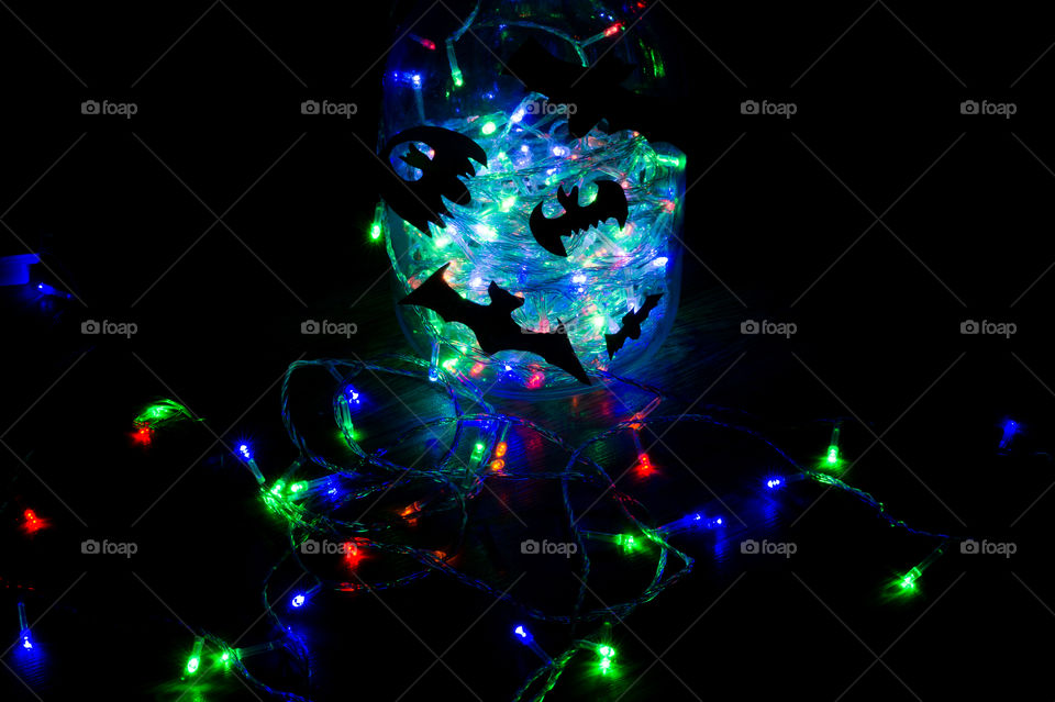 Halloween bats are glued to a glass jar with a garland glowing in it.