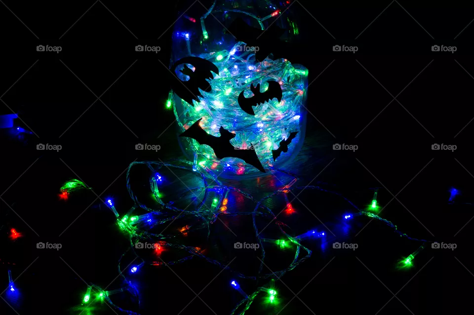 Halloween bats are glued to a glass jar with a garland glowing in it.