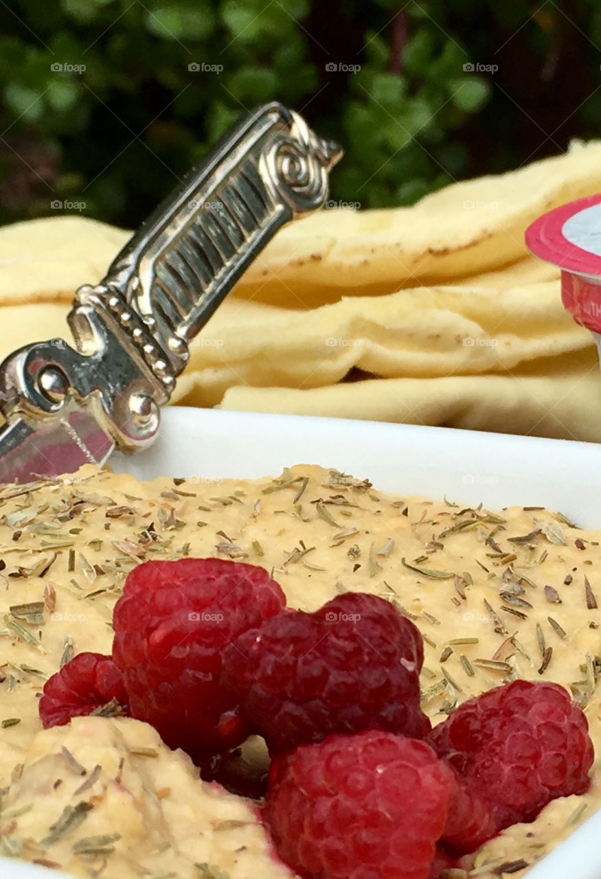 Red raspberries on dish of hummus dip 