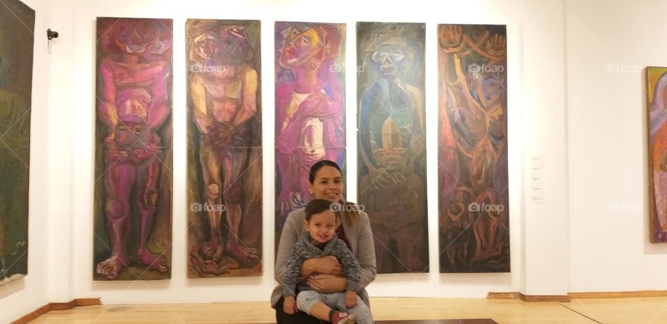 mother and baby in front of paintings