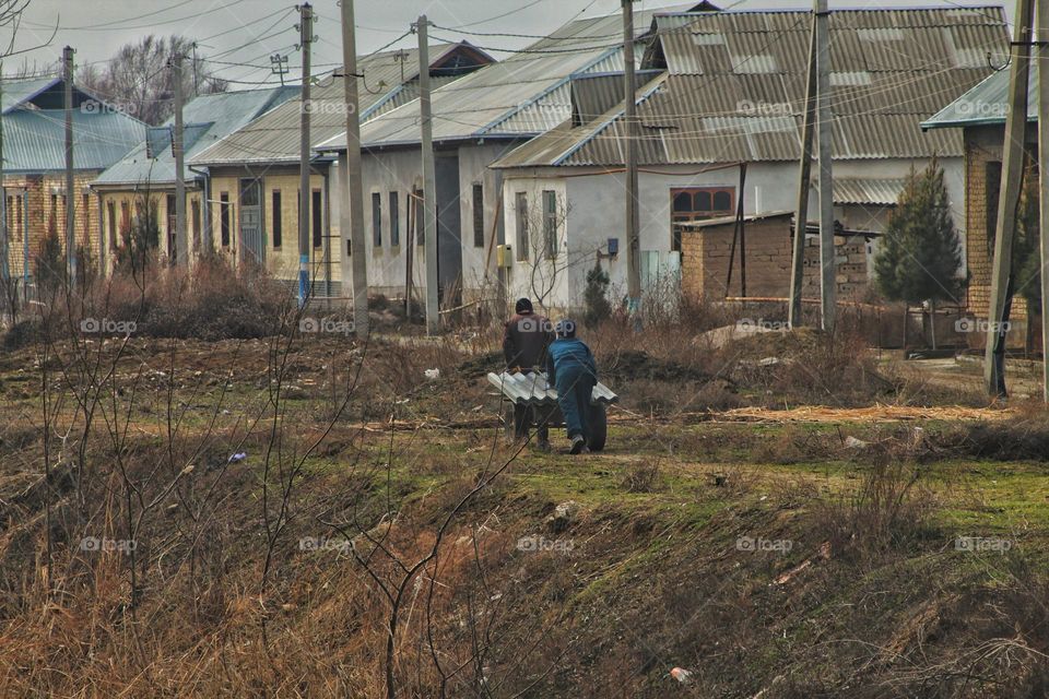 The story of how villagers educate the younger generation by their example and work.   since they do not have a car, father and son roll heavy roofing sheets on an ordinary cart. Strength is needed in the village