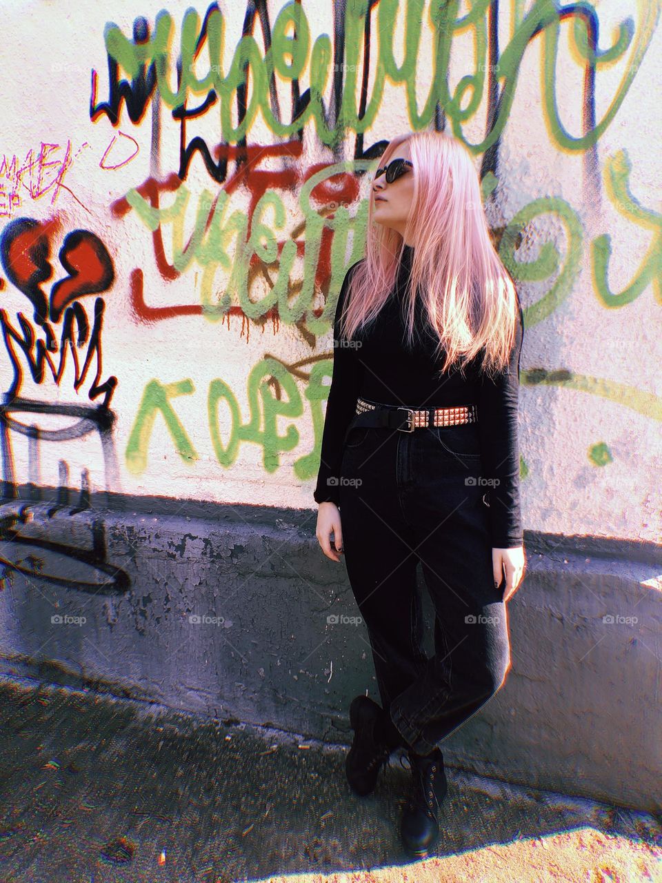 A young woman with pink hair on the background of a graffiti wall