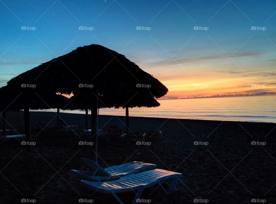 Shades of beach umbrellas and sunbeds at a beautiful sunset on the ocean