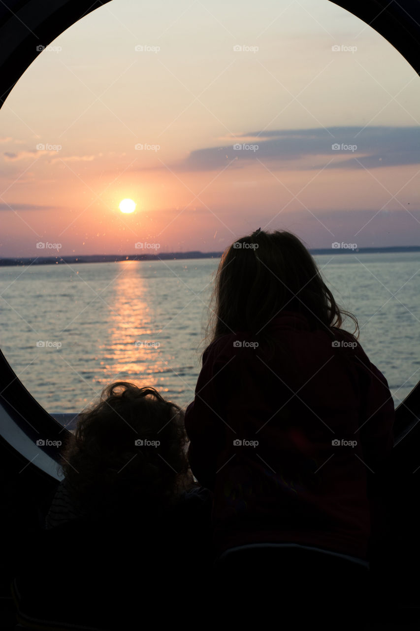 golden hour on sunrise. children on round window watching the golden hour in sunrise