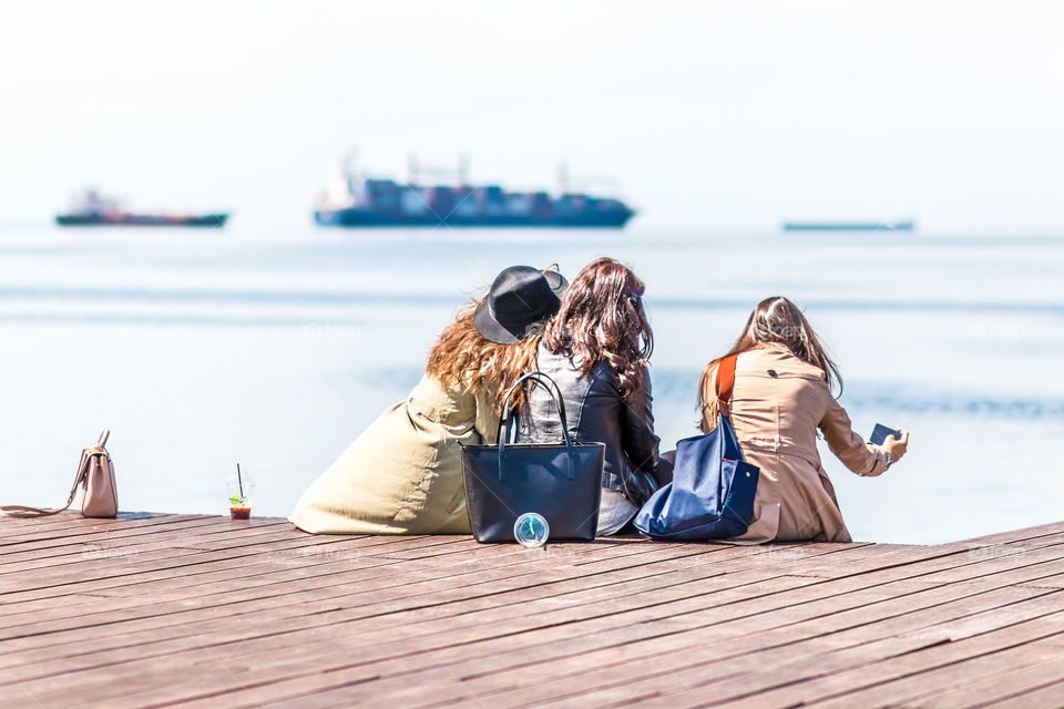 Young Girls Friends Taking Selfie And Using Mobile Phones At The Dock
