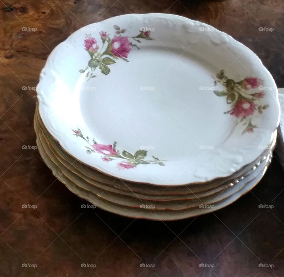 stack of white floral plates on brown table at Grandma's house referred to as The Good China