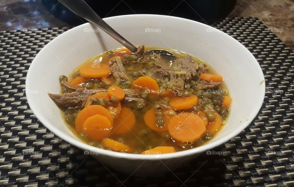 Delicious homemade beef broth soup with spoon.
