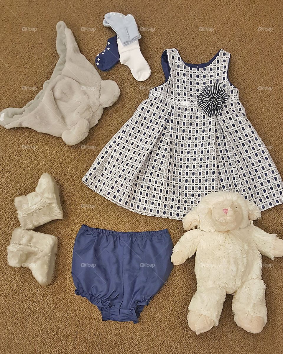 A baby girl outfit with a grey and navy theme; including a stuffed lamb, furry boots and a furry animal hat.